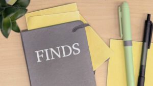 Notebook with sticky notes and pens on a wood desk The notebook is labeled "Finds."